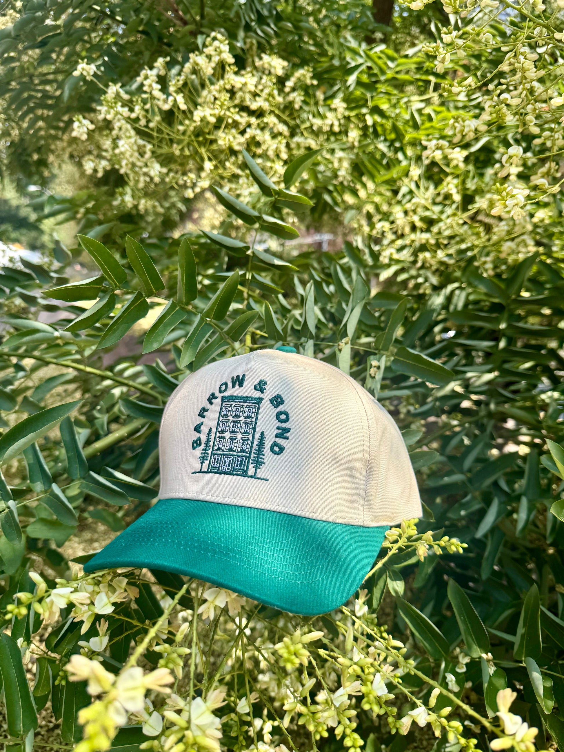 Cap with 'Barrow & Bond' logo on a green plant background