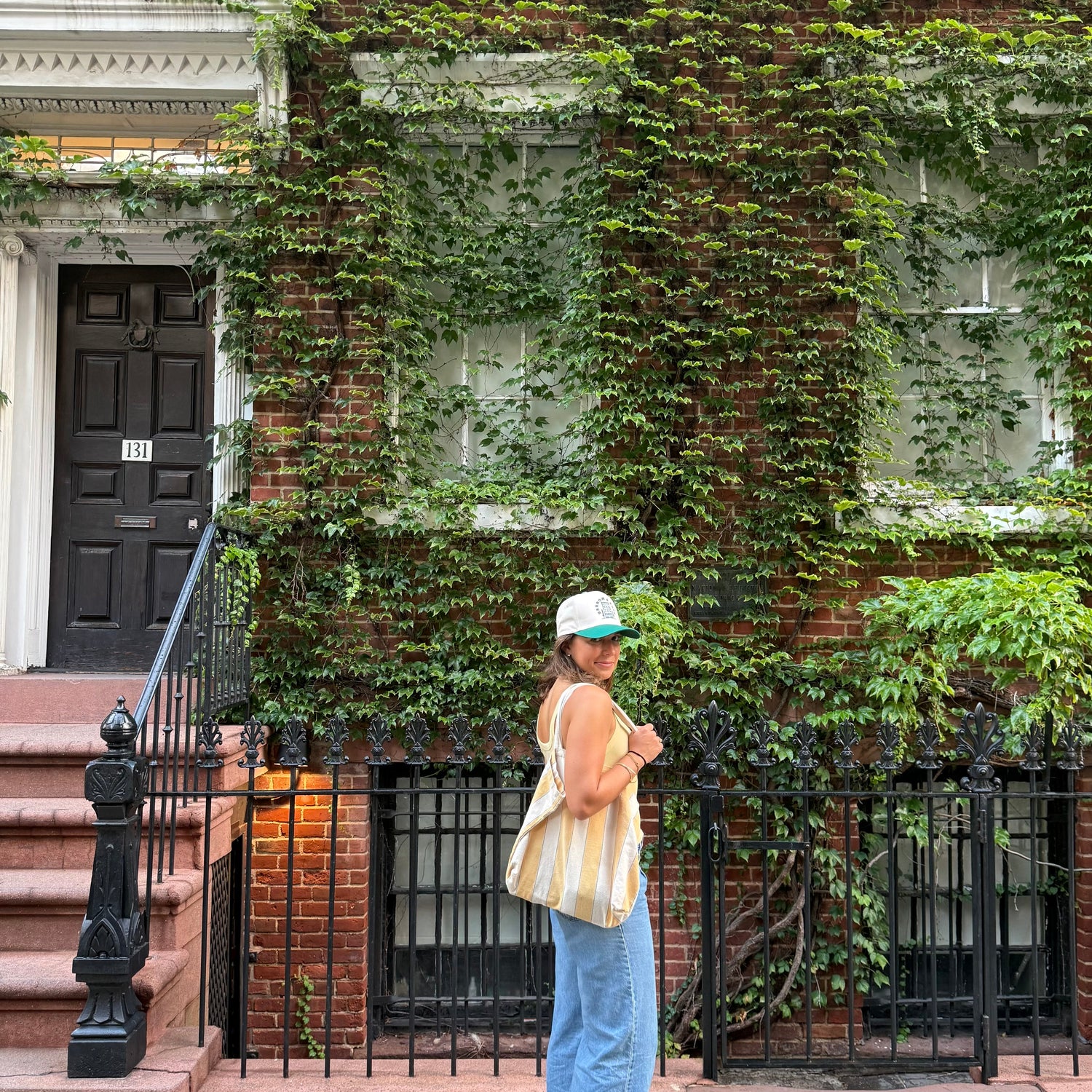 Person standing in front of a building with ivy-covered walls wearing barrow and bond hat