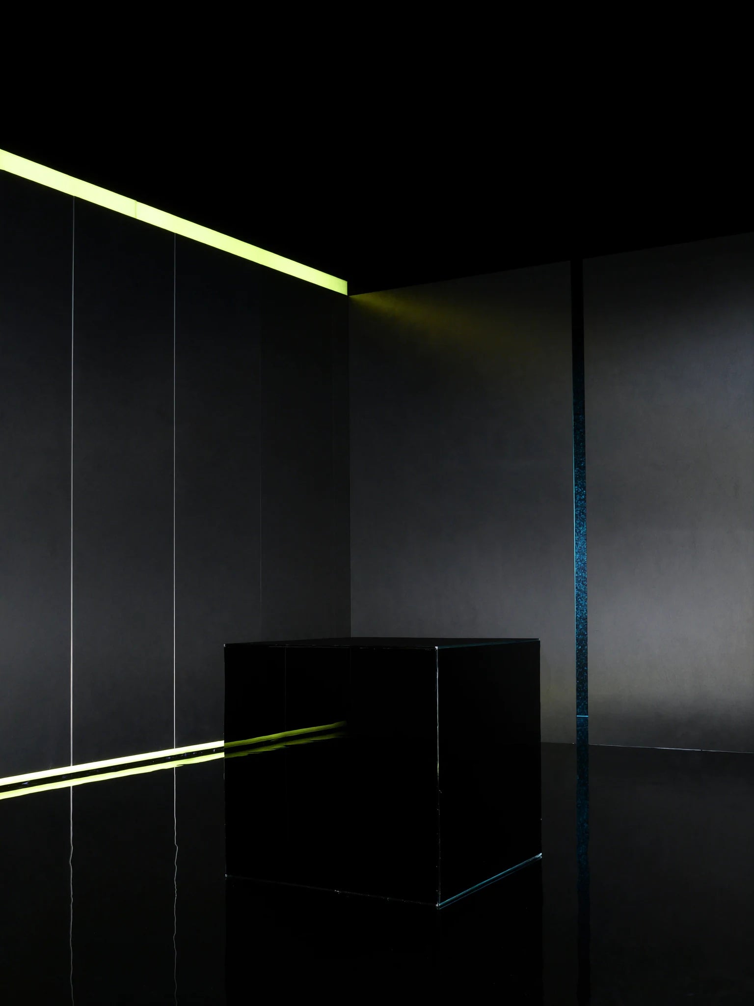 Dark graphite development studio with an acid-yellow light line and empty testing plinth